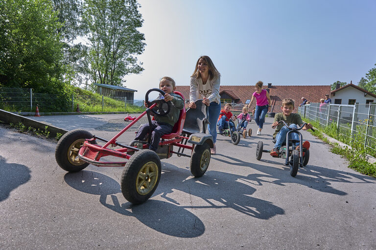 Kinder liefern sich ein Rennen auf GoKarts im bayerischen Wald.