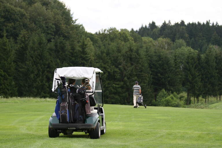 Ein Golfer fährt im Golfwagen über das Gras im Golfclub Bayerischer Wald.