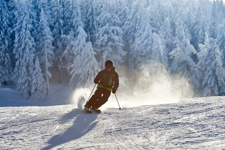 Ein Mann auf Skiern gleitet die weiße Piste des grossen Arbers hinunter.