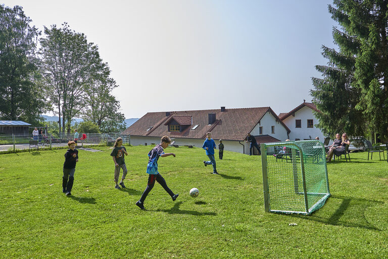 Kinder spielen Fußball im Urlaub auf dem Bauernhof.